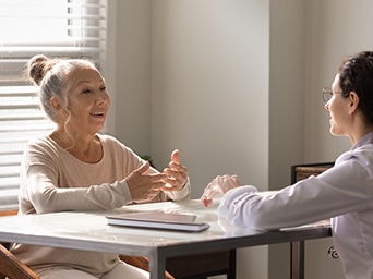 A woman sitting at a table talking to another woman